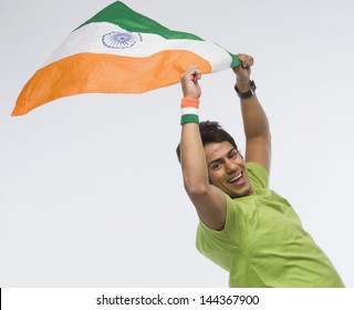 Portrait of a man holding aloft an Indian flag