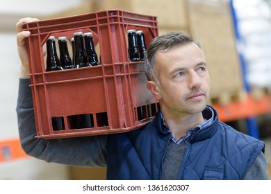 Portrait Of Man Holding Beer Bottles In Crate At Brewery