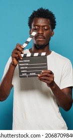 Portrait Of Man Holding Clapperboard To Cut Scenes In Movie Industry. Cheerful Person Using Chalkboard For Film Making Production And Cinematography In Studio. Young Adult With Clap Board