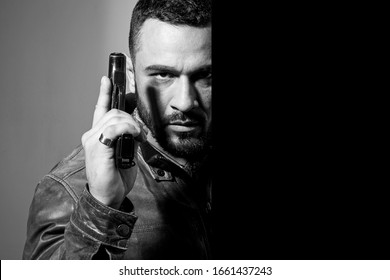 Portrait of a man holding gun. Handsome bearded man. Danger. Gunman with dark background. Serious stylish bearded man. Man with serious face and brutal style