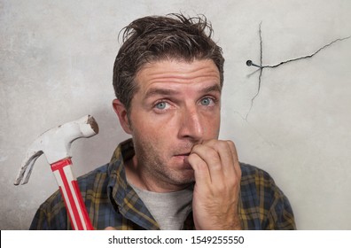 Portrait Of Man Holding Hammer Driving A Nail For Hanging A Frame But Making Funny Faces For The  Mess Cracking The Wall As A Disaster DIY Guy And Messy Domestic Repair Task At Home