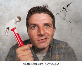 Portrait Of Man Holding Hammer Driving A Nail For Hanging A Frame But Making Funny Faces For The  Mess Cracking The Wall As A Disaster DIY Guy And Messy Domestic Repair Task At Home