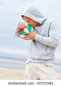 Portrait of man kissing ball on the beach
