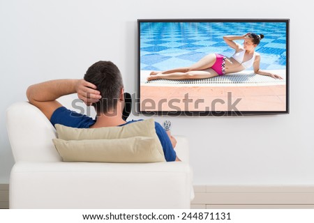 Portrait Of A Man Lying On Couch Watching Television At Home