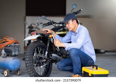 Portrait of man mechanic in garage or workshop inspecting classic motorcycle during the maintenance - Powered by Shutterstock