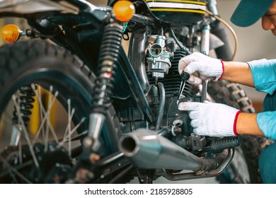 Portrait of man mechanic in garage or workshop inspecting classic motorcycle during the maintenance and checks oil level. - Powered by Shutterstock