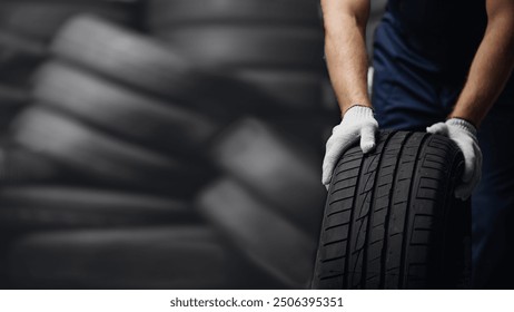 Portrait man mechanic holding new tyre on background store, car tire service concept.