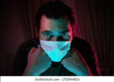 Portrait of a man in a medical mask. Isolation of the house in quarantine. The emotions of fear and impending doom. Global viral pandemic. The epidemic of coronavirus. Covid-19. 2019-nCoV. - Shutterstock ID 1702969816