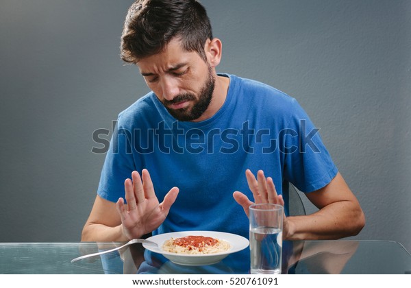 Portrait of man with no appetite in front of the\
meal. Concept of loss of\
appetite