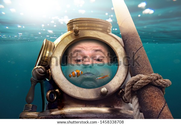 Portrait of man in old diving suit and helmet under\
water. Funny diver in retro equipment with water and fish inside\
his helmet .