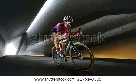 Portrait of man, professional cyclist training, riding on professional sport bike around city on tunnel in a daytime. Concept of sport, lifestyle, health, outdoor training, speed and endurance.