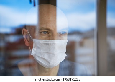 portrait of a man in a protective mask looks through the windows to the street - Shutterstock ID 1958191285
