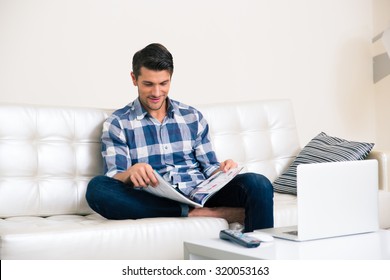 Portrait Of A Man Reading Magazine On The Sofa At Home 