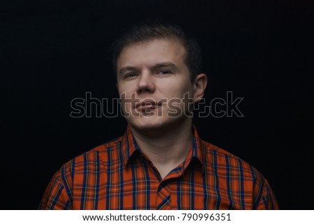 portrait of a man in a red shirt in a cell on a black background.