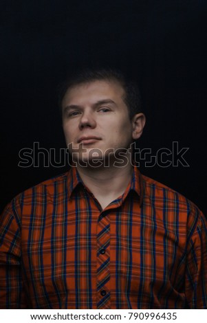 portrait of a man in a red shirt in a cell on a black background.