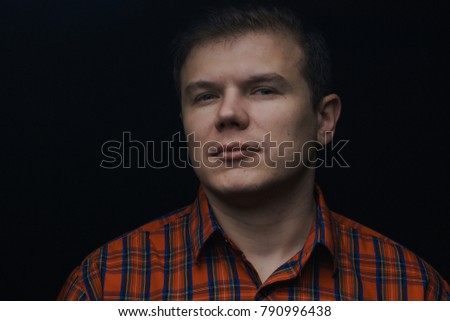 portrait of a man in a red shirt in a cell on a black background.