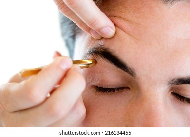 Portrait Of Man Removing Eyebrow Hairs With Tweezing.