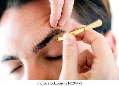 Portrait Of Man Removing Eyebrow Hairs With Tweezing.