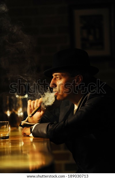 バーで葉巻を吸っている男のポートレート マフィア レトロまたはギャングスタイル の写真素材 今すぐ編集