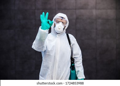 Portrait of man in sterile uniform and mask standing outdoors and showing okay sign. Surfaces are all sterilized from corona virus/ covid-19. - Shutterstock ID 1724853988
