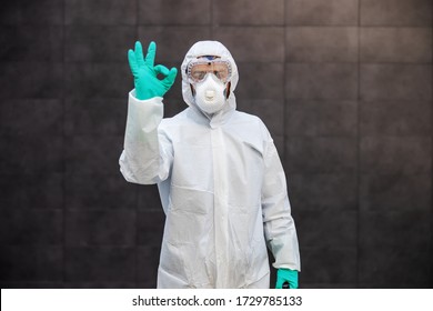 Portrait of man in sterile uniform and mask standing outdoors and showing okay sign. Surfaces are all sterilized from corona virus/ covid-19. - Shutterstock ID 1729785133
