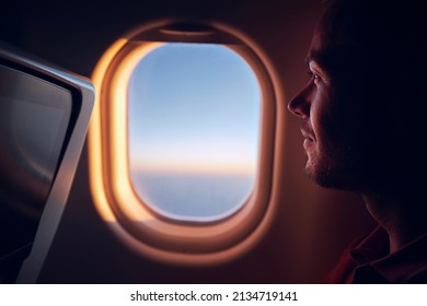 Porträt des Menschen, der mit dem Flugzeug reist. Fluggast, der während des Fluges bei Sonnenaufgang durch das Flugzeug schaut.
 – Stockfoto