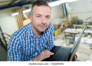 Portrait Of Man Using Laptop On Gallery Above Factory Floor