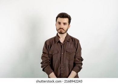 Portrait of man wearing brown shirt posing isolated over white background crying wipes tears losing his job. I don't know.