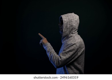 Portrait of man wearing sunglasses and hooded sweatshirt standing, motionless, making hand gestures. Isolated on dark background. - Powered by Shutterstock