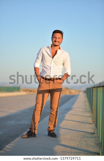 portrait of man\
wearing white shirt at the\
beach