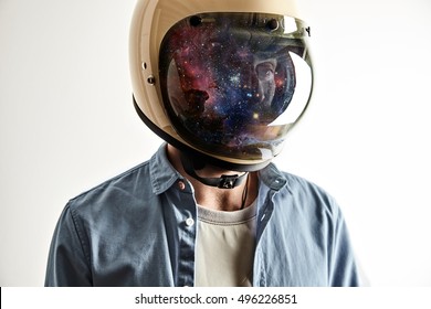 Portrait of a man in a white t-shirt and light blue denim shirt wearing a white motorcycle or space helmet with stars and galaxies reflected in the shield isolated on white. Double exposure - Shutterstock ID 496226851