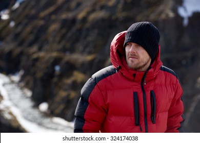 Portrait Of Man In Wilderness Rugged Mountain Landscape Determined To Climb To The Summit In Red Snow Gear