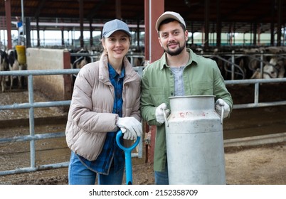 Portrait Of Man And Woman Dairy Farm Workers With Milk Can And Shovel.