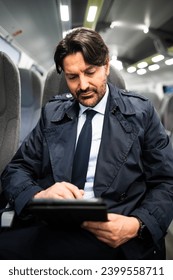 Portrait of a manager using his tablet while sitting on a train