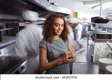Portrait of manager writing on clipboard in commercial restaurant