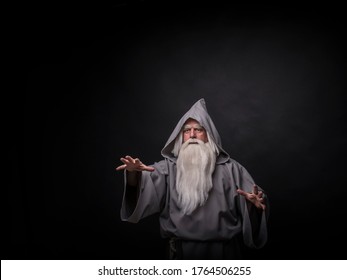 Portrait of a manly and brutal, majestic, old man, sorcerer, wizard with gray hair and a beard with a mustache, in gray clothes, a canopy and tunic on a gray background - Shutterstock ID 1764506255