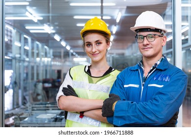 Portrait Of Manual Man And Woman Worker Is Standing With Confident With Blue Working Suite Green Reflect For Safety Dress And Helmet In Front The Glass Wall Of High Technology Clean Industry Factory.