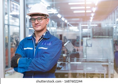 Portrait of manual man worker is standing with confident with blue working suite dress and safety helmet in front the glass wall of high technology clean industry factory.