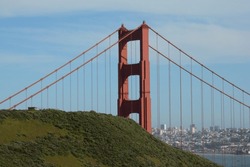 Portrait Of The Marin Side Of The Golden Gate Bridge, With The San Francisco Art Museum And City Skyline Visible Beyond The Hills Of The Marin Headlands In San Francisco, California, USA