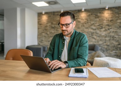Portrait of marketing manager typing over laptop computer while working seriously at desk in office