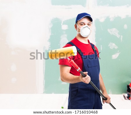 Portrait of a masked painter at work in an apartment, renovation and home painting during coronavirus pandemic