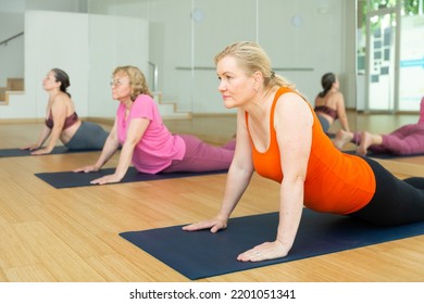 Portrait Of Mature Active Woman Practicing Yoga In Group, Making Stretching Asana