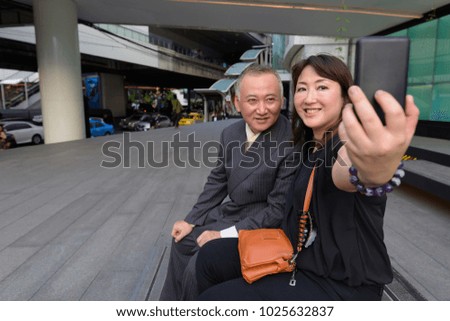 Portrait of mature Asian businessman and mature Asian woman exploring the city of Bangkok, Thailand