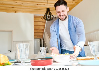 Portrait Of Mature Bearded Man Setting Table And Smiling Happily While Waiting For Guests At Dinner In Sunlit Dining Room At Home, Copy Space