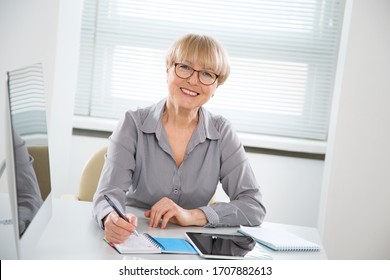 Portrait of mature business woman looking at camera at workplace in an office