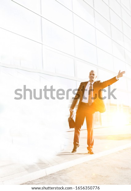 Portrait of mature businessman calling taxi in\
the airport