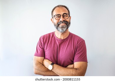 Portrait of mature businessman. Male executive is wearing T-shirt. Professional is smiling against gray background. Confident businessman with arms crossed. Mature mixed race man smiling