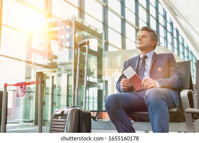 Portrait of Mature businessman sitting and holding his passport while waiting in gate for boarding at airport - Powered by Shutterstock