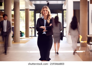 Portrait Of Mature Businesswoman CEO Standing In Lobby Of Busy Modern Office Building