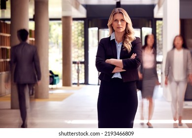 Portrait Of Mature Businesswoman CEO Standing In Lobby Of Busy Modern Office Building